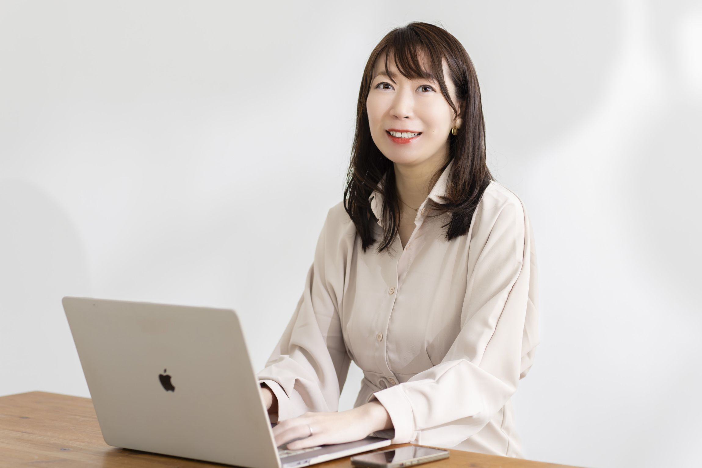 机のノートパソコンに手を置き、こちらを見てほほえむUmi Design代表の田村渚。千葉ホームページ相談室の運営者